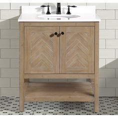 a white sink sitting under a wooden cabinet next to a tiled bathroom floor with black and white tiles on the walls