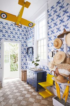 a room with blue and white wallpaper, an airplane hanging from the ceiling and several hats on display