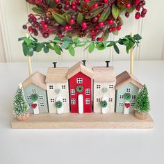 a christmas scene with houses and trees on a table next to a potted plant