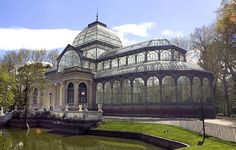 a large glass house sitting on top of a lush green field next to a pond