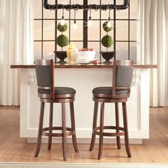 two bar stools sitting in front of a window with potted plants on it