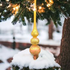 a christmas ornament hanging from a tree in the snow