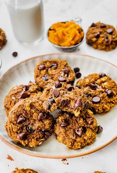 chocolate chip cookies on a plate next to a glass of milk and pumpkin puree