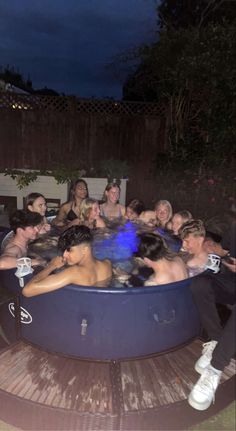 a group of people sitting in an outdoor hot tub with blue lights on the side