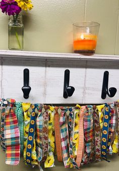 a bunch of ribbons hanging from hooks on a wall next to a vase with flowers