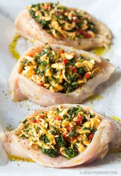 three pieces of raw chicken with herbs and seasoning on them sitting on a white plate