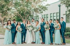 a group of people standing next to each other in front of a building holding bouquets