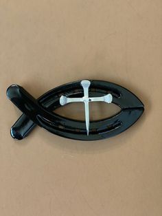 a black and white object with a cross on it's center piece in the shape of a fish