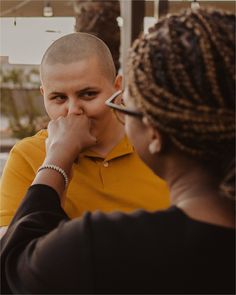 a woman is talking to a man who is holding his hand up to his mouth