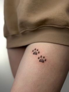 a person with a small tattoo on their leg that has two paw prints in it