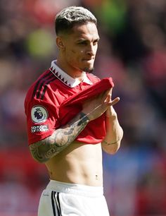 a shirtless man with tattoos on his chest holding a soccer ball in front of him