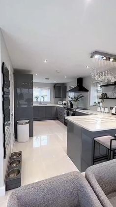 a modern kitchen and living room are shown in this image, with grey cabinets and white flooring