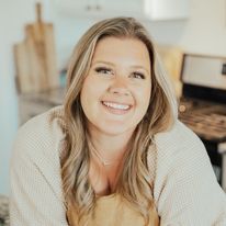 a woman sitting in front of an oven smiling