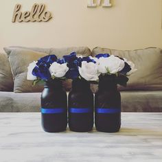 three blue and white flowers are in black vases on a table next to a couch