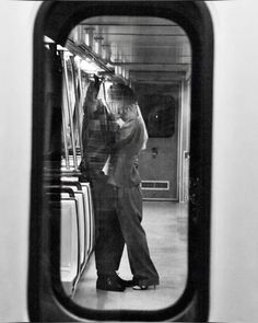 a man and woman standing next to each other in front of a train car window