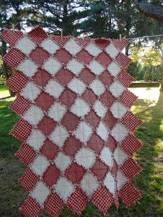 a red and white quilt hanging from a tree