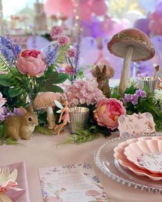 a table topped with lots of pink flowers and bunny figurines on top of it