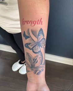 a woman's arm with a butterfly tattoo on it and the words strength written in red