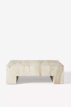 a white marble coffee table sitting on top of a white floor next to a wall