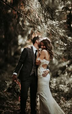 a bride and groom kissing in the woods