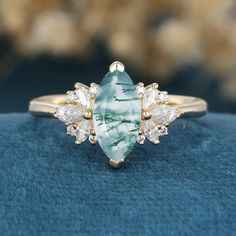 a green and white stone ring sitting on top of a blue cloth