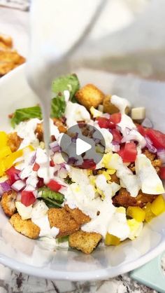 a white bowl filled with salad and dressing being drizzled on top of it