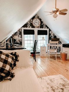 an attic bedroom with black and white wallpaper, wood flooring and ceiling fan