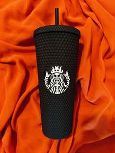 a starbucks cup sitting on top of an orange blanket