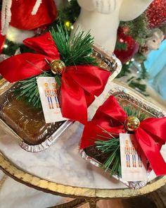 two pieces of cake on a tray with red bows and decorations around the edges, sitting on a table in front of a christmas tree