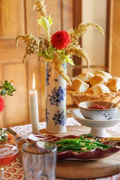 a table with bread and flowers in a vase on it, next to a candle