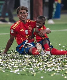 two soccer players sitting on the ground with confetti all over their feet and arms