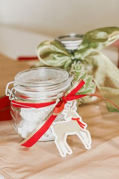 a glass jar filled with white sugar sitting on top of a table next to a red ribbon