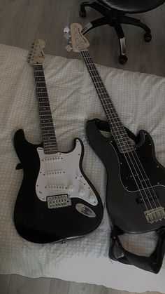 two electric guitars are laying on a bed