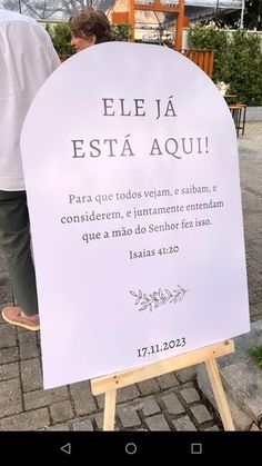 a white sign sitting on top of a wooden easel in front of a building