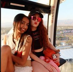 two women sitting on the back of a cable car with their arms around each other