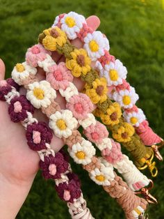 four crocheted flower bracelets are held in someone's hand