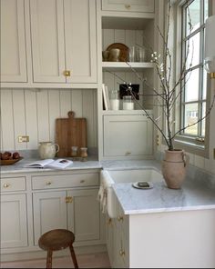 a kitchen with white cabinets and marble counter tops, an open window above the sink