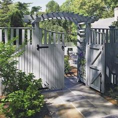 an open gate leading into a garden with potted plants