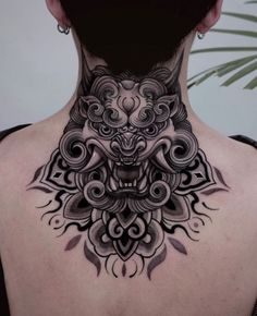 the back of a woman's neck with an intricate tattoo design on her chest