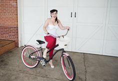 a woman in red pants riding a bike with a basket on the front and side