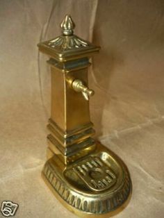 an antique brass clock is on display in a glass case with a white cloth behind it