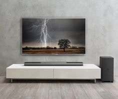 a large flat screen tv mounted on the wall above a white entertainment center with speakers