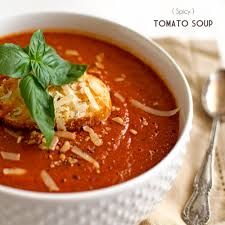 a white bowl filled with tomato soup and garnished with parmesan cheese