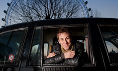 a man sitting in the driver's seat of a car next to a ferris wheel