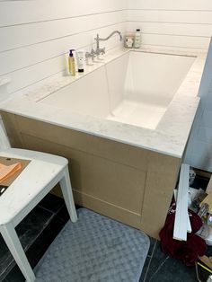 a white sink sitting next to a bath tub in a bathroom on top of a hard wood floor