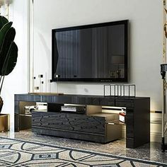 a living room with a large television mounted on the wall and a plant in front of it