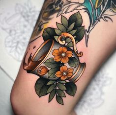 a woman's leg with flowers and a tattoo on it, including an orange flower