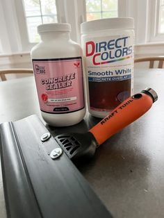 two bottles of paint and an orange marker sitting on a table next to a pair of scissors