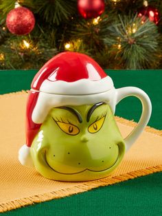 a grin face mug with a santa hat on it's head sitting on a place mat