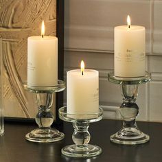 two candles are sitting in glass holders on a table